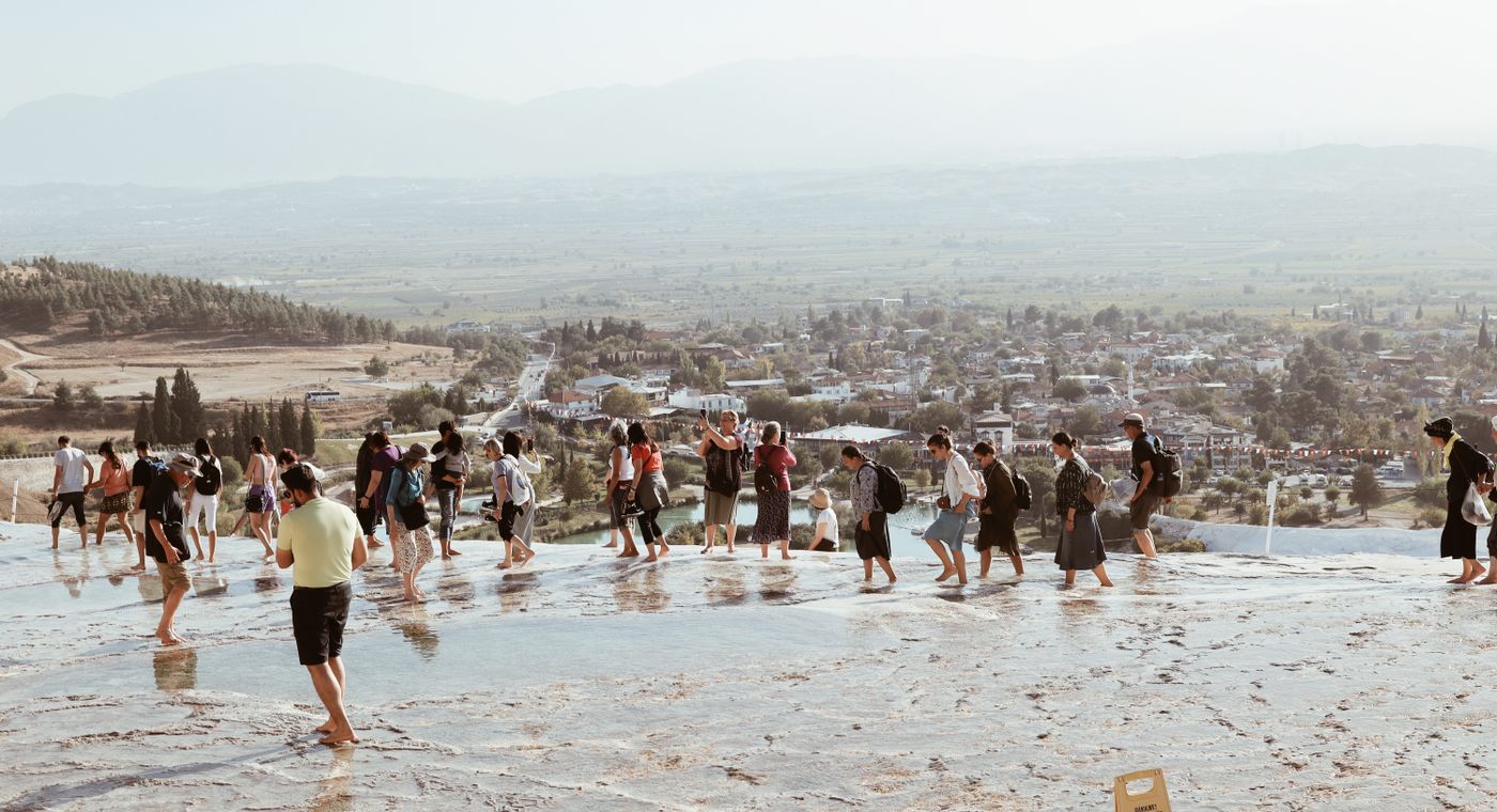 Gün batımında Pamukkale’nin beyaz travertenleri ve ziyaretçiler